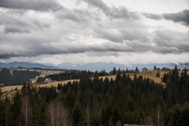 Bulutlu Gökler Altında Huzurlu Dağ Manzarası.