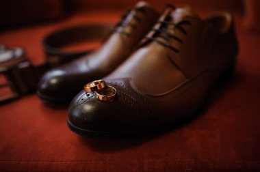 Kadife bir yüzey üzerinde alyansları olan zarif kahverengi ayakkabılar..