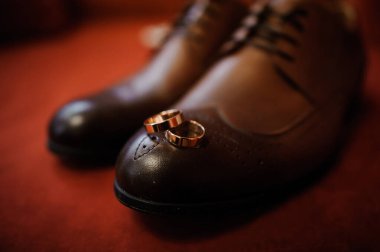 Zarif alyanslar cilalanmış kahverengi deri ayakkabıların üzerinde dinleniyor..