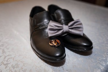 Siyah pabuçlar, papyon ve nikah yüzüklerinin olduğu zarif bir düğün elbisesi..