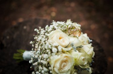 Gülleri ve alyansları olan zarif düğün buketi..