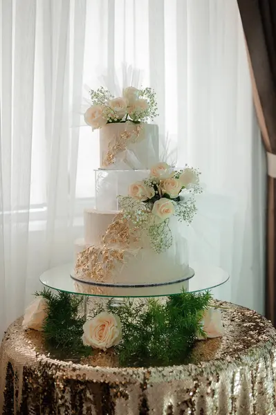 Zarif Beyaz Düğün Pastası Taze Çiçekler ve Altın Aksanlarla süslenir.