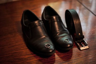 Tahta bir yüzeyde kemeri olan zarif siyah deri ayakkabılar..