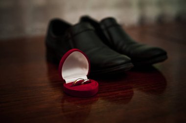 Elegant Wedding Rings on a Polished Surface Near Black Formal Shoes. clipart