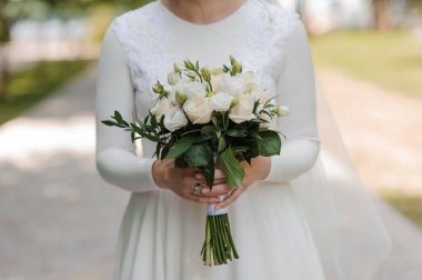 Zarif Gelin, Beyaz Gül Buketini Doğal Bir Açık Hava Ayarında Tutuyor.