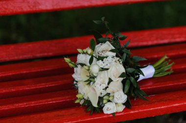 Şık Beyaz Çiçek Buketi, canlı kırmızı bir bankta sergileniyor..