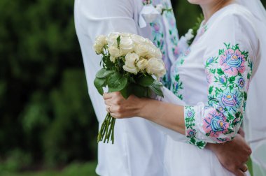 Geleneksel Nakışlı Beyaz Gülleri Tutan Gelin ile Romantik Açık Hava Düğün Töreni.