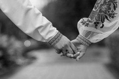 Geleneksel Giyimde İki Elin Tutuşunun Zarif Siyah ve Beyaz Fotoğrafı.