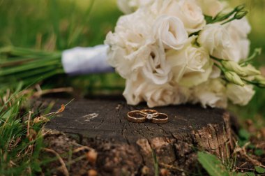 Beyaz Çiçek Buketinin Yanındaki Tahta Kütükte Alyanslar.