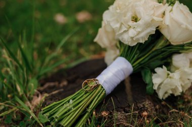 Kırsal bir kütükte alyansları olan zarif gelin buketi..