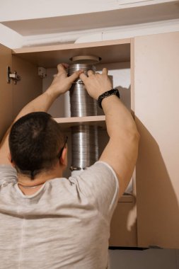 Mutfak Dolabında Metal Kutularla Rafları Düzenleyen Adam.