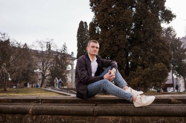 Genç Adam Şehir Parkı Ayarlarında Rahatça Oturuyor.