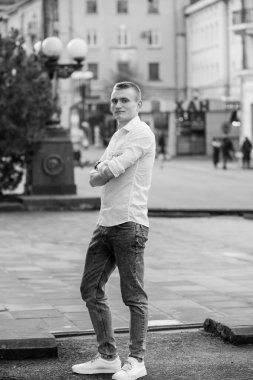 Günlük kıyafetli genç adam Şehir Caddesinde güven içinde poz veriyor..