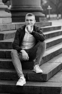 Monokrom 'da Taş Merdivenlerde Oturan Düşünceli Genç Adam.