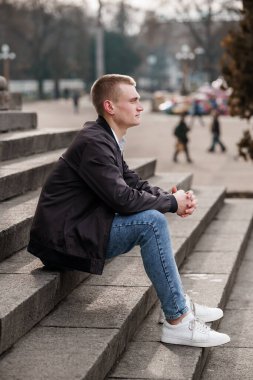 Şehir parkında Basamaklarda Yansıyan Günlük Giyimli Genç Bir Adam.