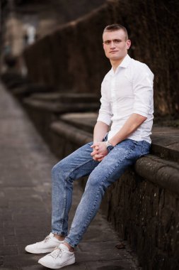 Şık Genç Adam Şehir Merkezinde Taş Duvarda Oturuyor.