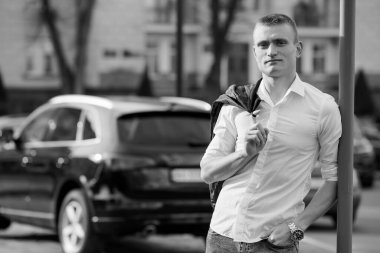 Şık Genç Adam Arka planda Şatafatlı Otomobille Şehir Ayarlarında Kendine Güvenle Poz Veriyor.