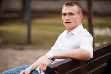 Günlük kıyafetlerle Park Bençinde Rahatlayan Genç Bir Adam.