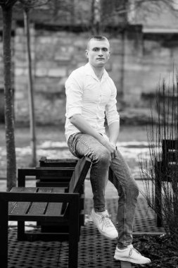 Serene Outdoor 'daki Black Bench' te oturan genç bir adam..