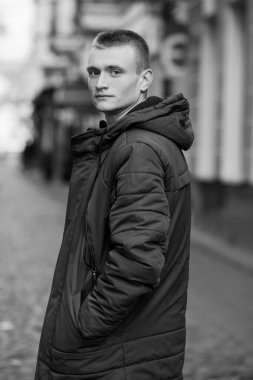 Portrait of a Young Man in a Casual Puffer Jacket on a Cobblestone Street. clipart