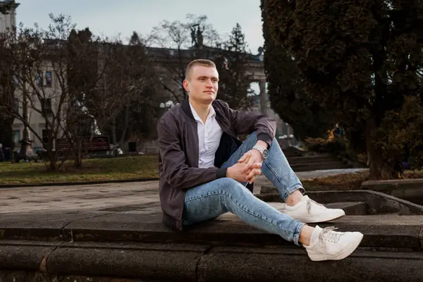 Huzurlu Park 'ta Taş Duvarda Rahatlayan Genç Adam.