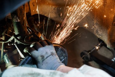 Kaynak sırasında kıvılcımlarla uçan bir araba üzerinde çalışan tamirci..