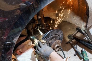 A Mechanic Performing Brake Maintenance Under a Car. clipart