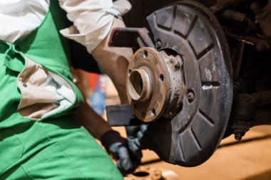 Bir atölyede araba frenleme diski üzerinde çalışan bir tamircinin yakın çekimi.