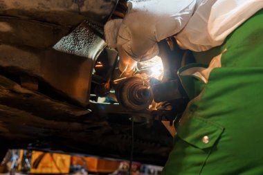 Mechanic Performing Maintenance on a Car Underbody. clipart