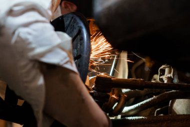 Kıvılcımlarla uçan makineler üzerinde çalışan yetenekli bir tamirci..