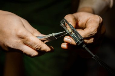 Elektrik kablolarını hassas araçlarla tamir eden bir zanaatkar.