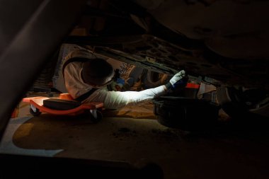 Karanlık Garajda El Feneri Denetleme Aracıyla Araba Altında Çalışan Tamirci.