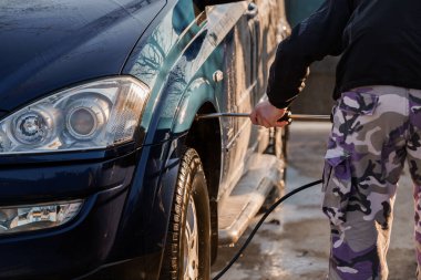 Açık Otomobil Yıkama İstasyonu 'nda yüksek basınçlı çamaşır makinesi kullanan Koyu Mavi SUV..