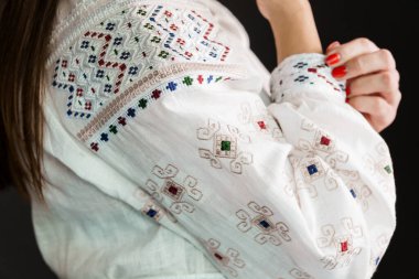 Geleneksel Beyaz İşlemeli, Etnik Dekoratif Desenli Beyaz Kumaşın ve Kadın Eli 'nin Yakın Çekimi.