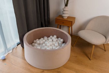 Modern Mobilya Yakınlarındaki Beyaz Toplarla Dolu Yuvarlak Bej Top Çukuru İçten Oyun Alanı.