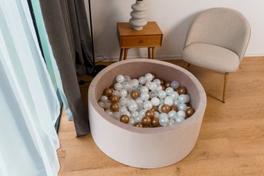 Modern İçişleri Odasında Beyaz ve Bronz Taşaklı Yuvarlak Bej Top Çukuru Doğal Işık Odası.