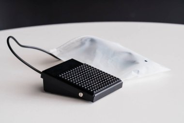 Beyaz yüzeyde Kablo ile Siyah Ayak Anahtarı Pedalı Şeffaf Steril Torba.