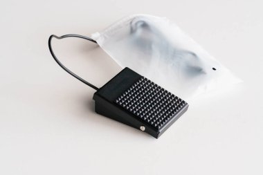 Tarafsız Arkaplanda Siyah Ayak Pedalı Kablo ve Beyaz Plastik Paketleme.