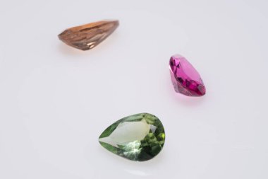 Beyaz Arkaplanda Yeşil, Pembe ve Kahverengi tonlarında Üç Kesik Değerli Gemstone.
