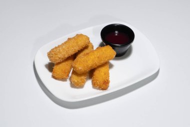 Altın Kızarmış Mozzarella Çubukları Beyaz bir tabakta tatlı sosuyla servis edilir..