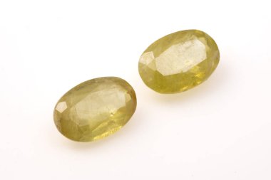 Beyaz arka planda iki oval şekilli, parlak, şeffaf, yeşil, doğal sfenen taşı..