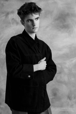 Siyah beyaz bir portre, kıvırcık saçlı, koyu renk ceketli ve kolları göğsünde çaprazlanmış bir şekilde kameraya bakan genç bir adam..