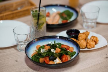 Somon salatası, içecek, aperatifler ve ahşap yüzeyde boş tabaklar ile nefis bir restoran masası..