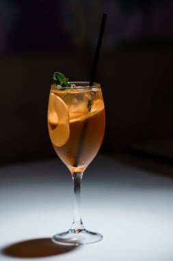Şarap kadehini portakal dilimi, buz küpleri ve arka planda nane şekeri ile tazeleyen kokteyl, bar veya restoran promosyonu için mükemmel..