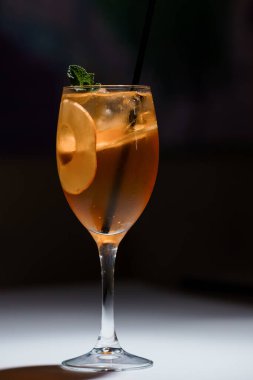 Şarap kadehinde elma dilimi ve nane ile canlandırıcı kokteyl, koyu arka planda hafif yüzeyde buzla servis edilir..