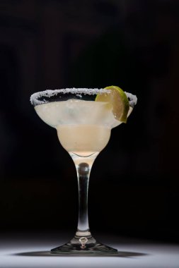 Koyu arka planda servis edilen tuzlu jöle ve limonlu bardakta klasik margarita kokteyli..