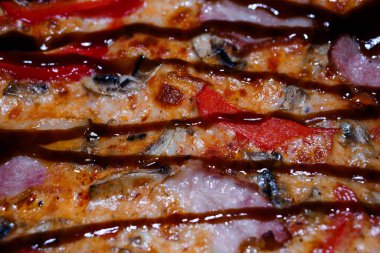 Kırmızı biberli, mantarlı ve jambonlu dilimlenmiş pizza. Peynirli dokular ve canlı renklerde lezzetli malzemeler sergileniyor..