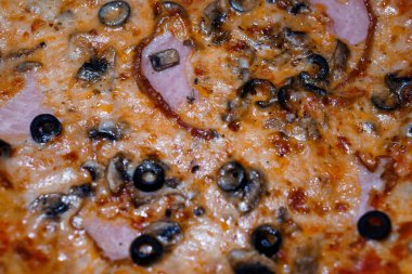 Jambonlu, mantarlı ve erimiş peynirli siyah zeytinli bir pizzanın enfes yakın çekimi, canlı renkler ve iştah açıcı dokular..