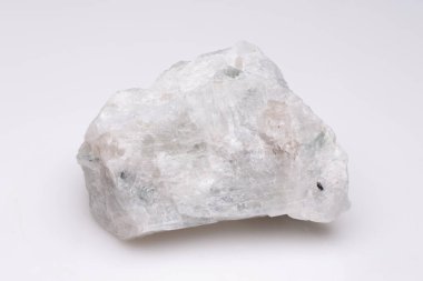 Kaba, şeffaf bir mineral örneğinin yakın görüntüsü ince yeşil renkler ile düz beyaz arka plan üzerinde, kristal yapısı ve doğal dokusunu sergiliyor..