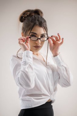 Gözlüklü genç bir kadın kameraya bakarken onları ayarlıyor..
